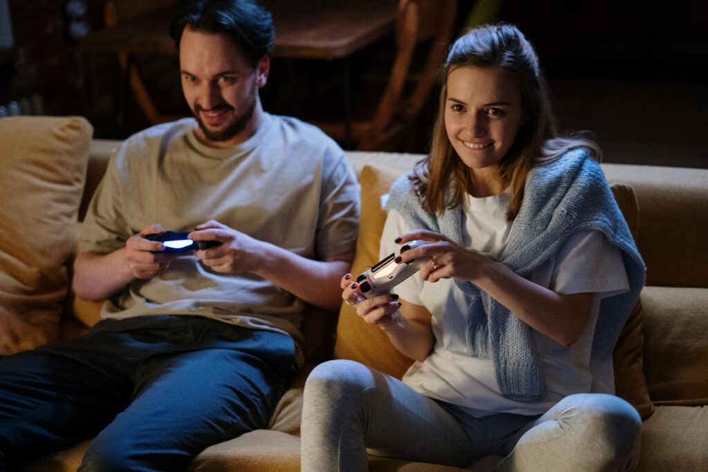 Happy couple gaming at home on sofa, enjoying quality time together.