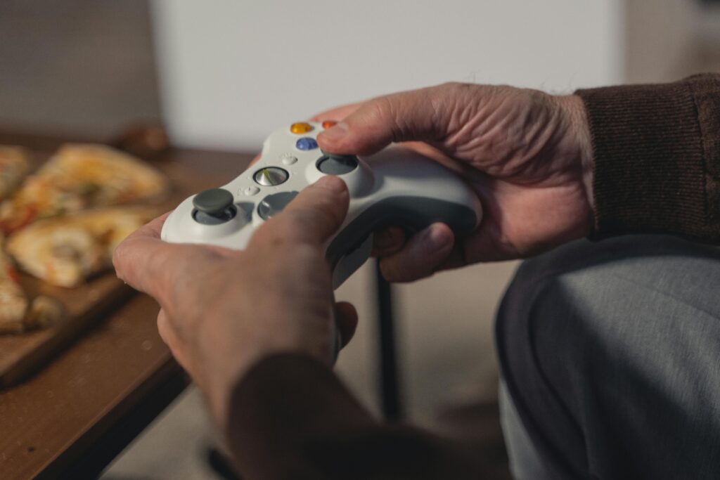 A senior adult holding a game controller, enjoying a leisurely moment indoors.