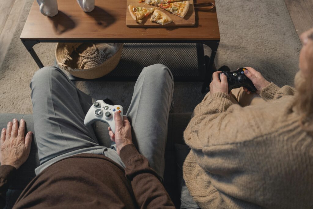 Elderly couple playing video games on the sofa, enjoying leisure time with a console.